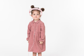 ピンクのヘッドフォンを着ているピンクのドレスの子供女の子