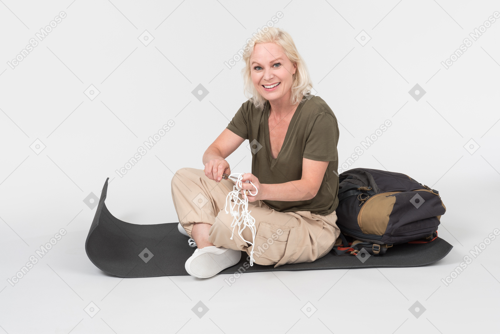 Mature female tourist sitting on tourist mat near the backpack