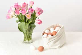 Bolsa de lino con huevos de gallina y ramo de tulipanes