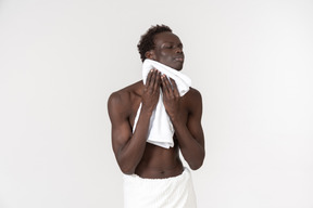 A young black man with a white bath towel around his waist doing his morning routine
