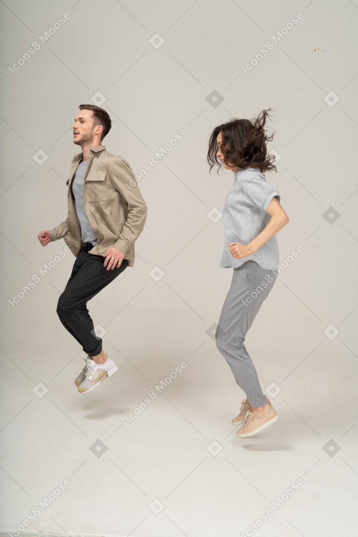 Side view of young man and woman jumping