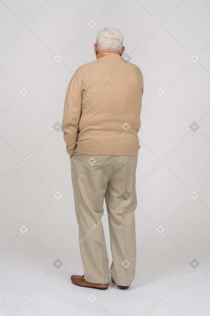 一位身穿休闲服的老人手插口袋站立的后视图
