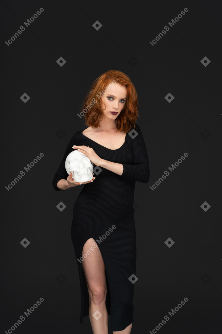 A frontal view of a sexy beautiful girl holding a skull