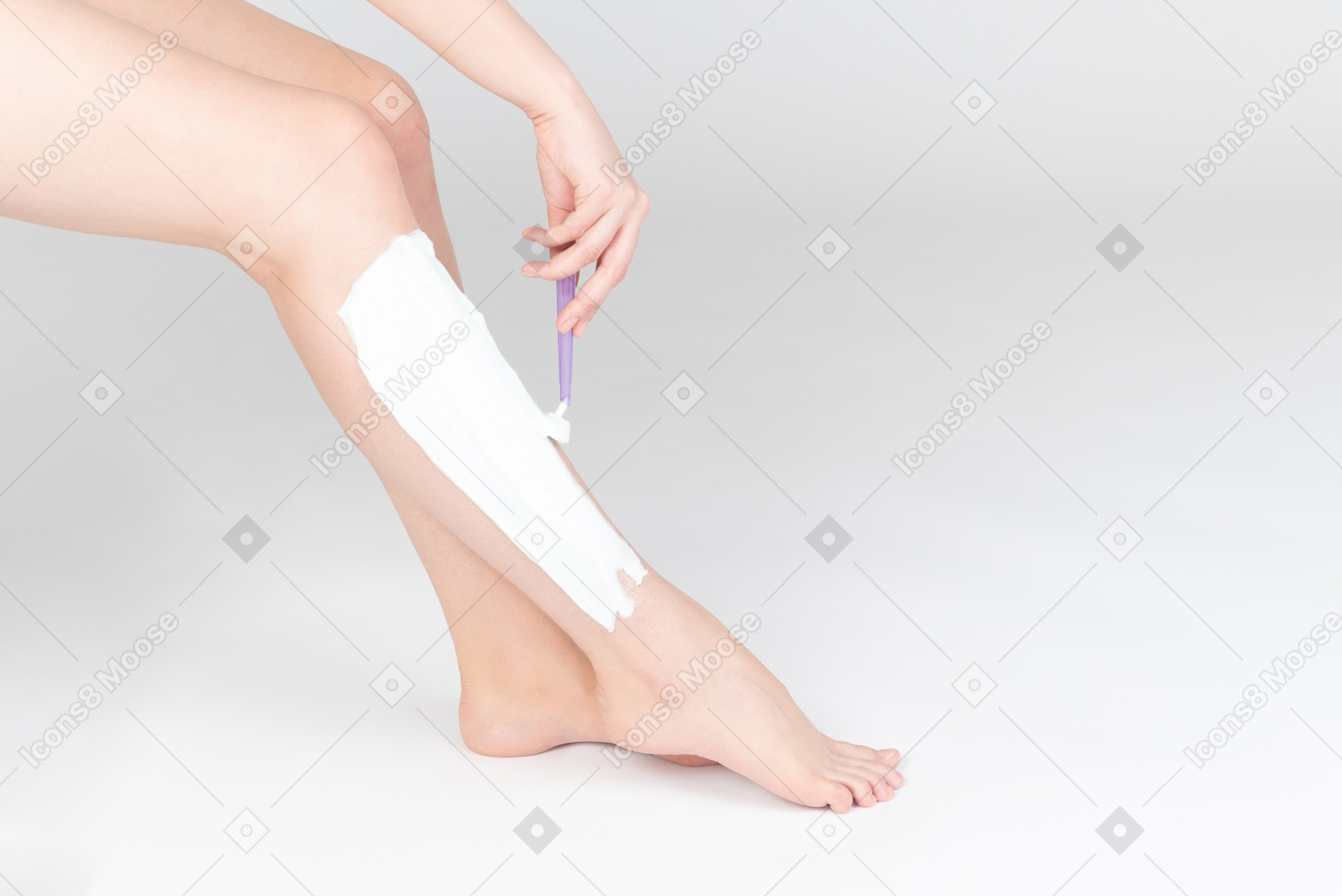 Shot of female legs and woman shaving them