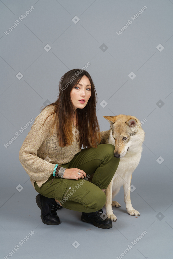 Full-length of a female master sitting by her dog and looking at camera