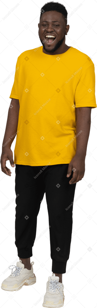 Vista frontal de un joven de piel oscura riendo en camiseta amarilla