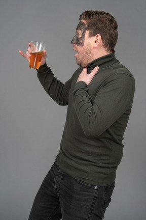 Side view of a surprised male football fan holding a beer