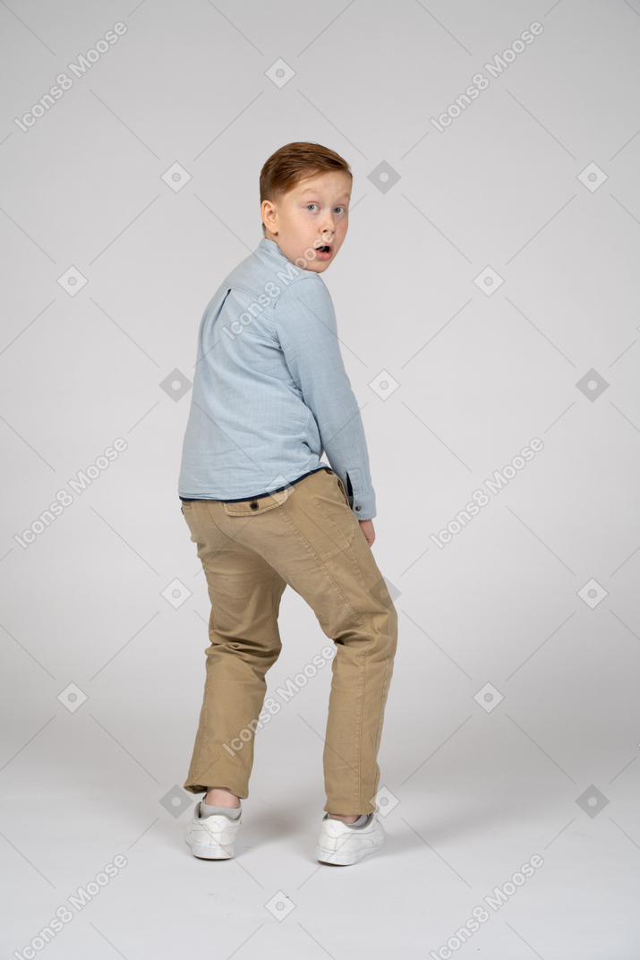 Back view of an impressed boy looking at camera