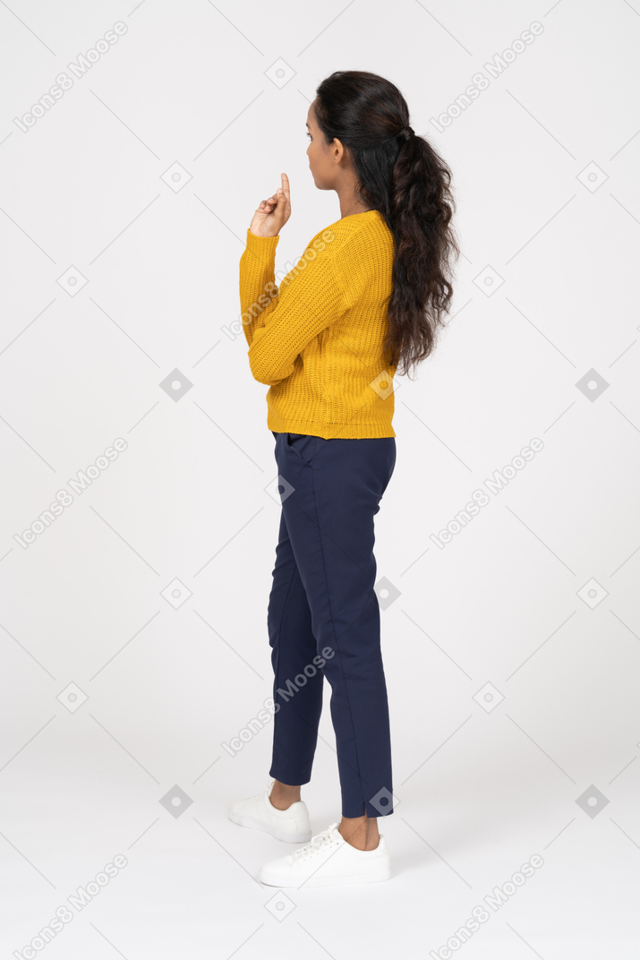 Вид сбоку задумчивой девушки в повседневной одежде, указывая пальцем вверх