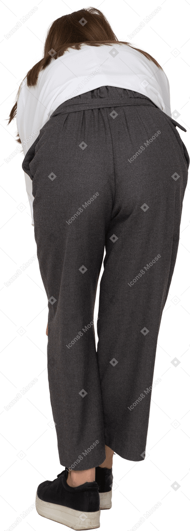Vista posterior de una joven en ropa de oficina agacharse y tocar la rodilla