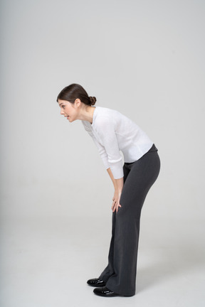 Side view of a woman in white shirt and black pants bending down