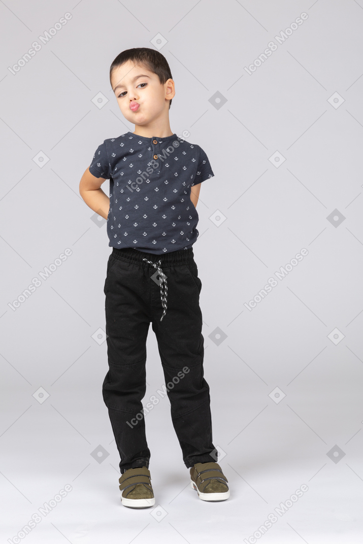 Front view of a cute boy posing with hands on back and making faces