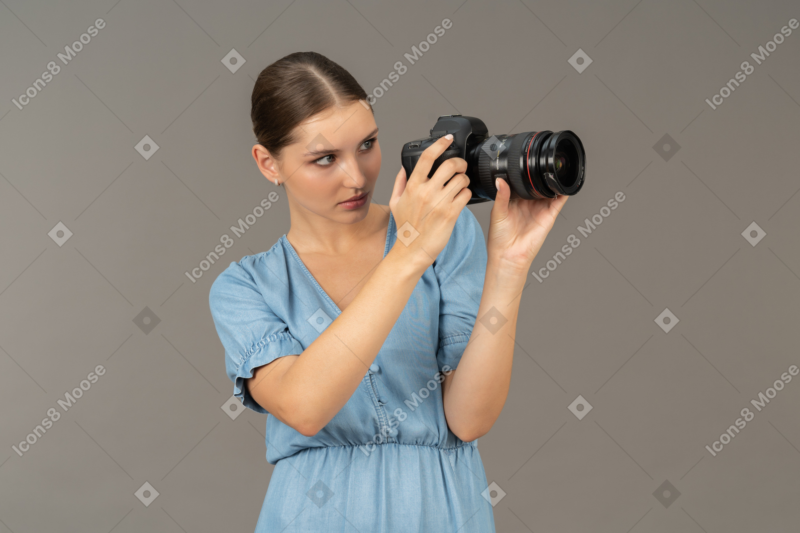 Three-quarter view of a young woman in blue dress taking shot