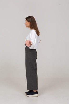 Side view of a young lady in office clothing outspreading arms
