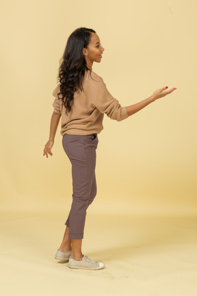 Side view of a dark-skinned young female outstretching her hand