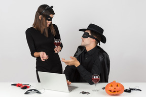 Colleagues in cat and zorro costumes talking and having wine