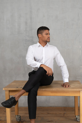 Well-dressed man sitting on a table with his head turned