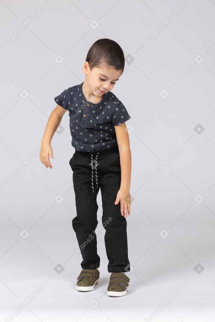 Vista frontal de un chico lindo que se inclina y trata de tocar el suelo.