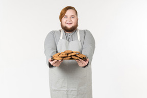 Um padeiro gordo sorridente oferecendo biscoitos