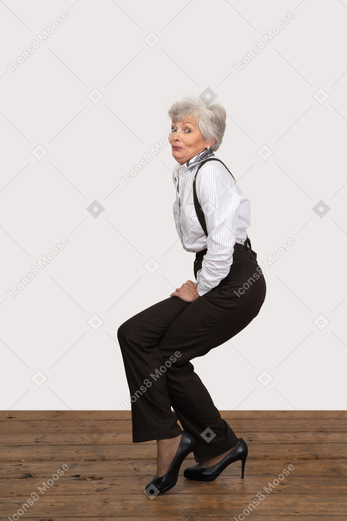 Vista lateral de uma mulher em roupas de escritório fazendo meio agachamento