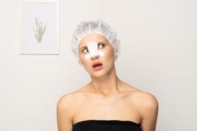 Amazed female patient with nose bandage looking aside