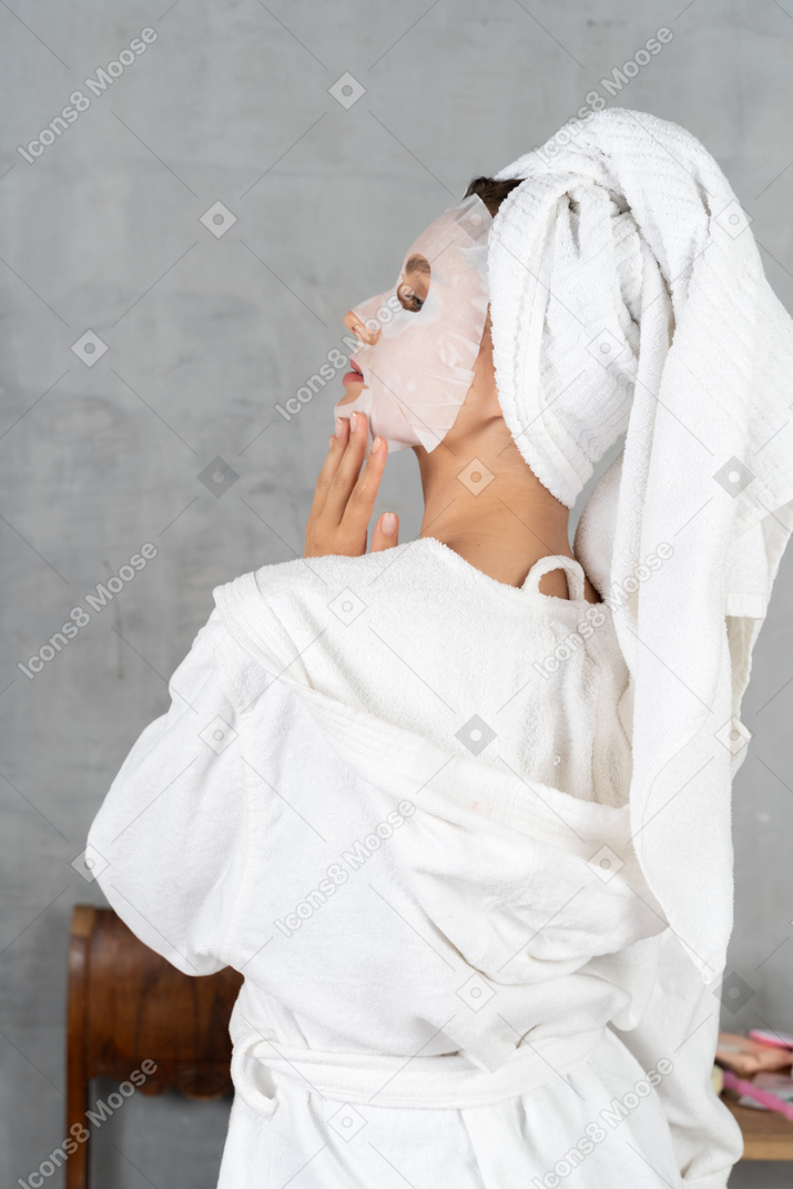 Vista traseira de uma mulher de roupão com uma máscara facial
