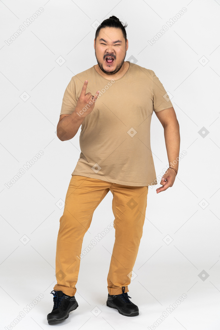Excited asian man looking at camera and making a rock gesture