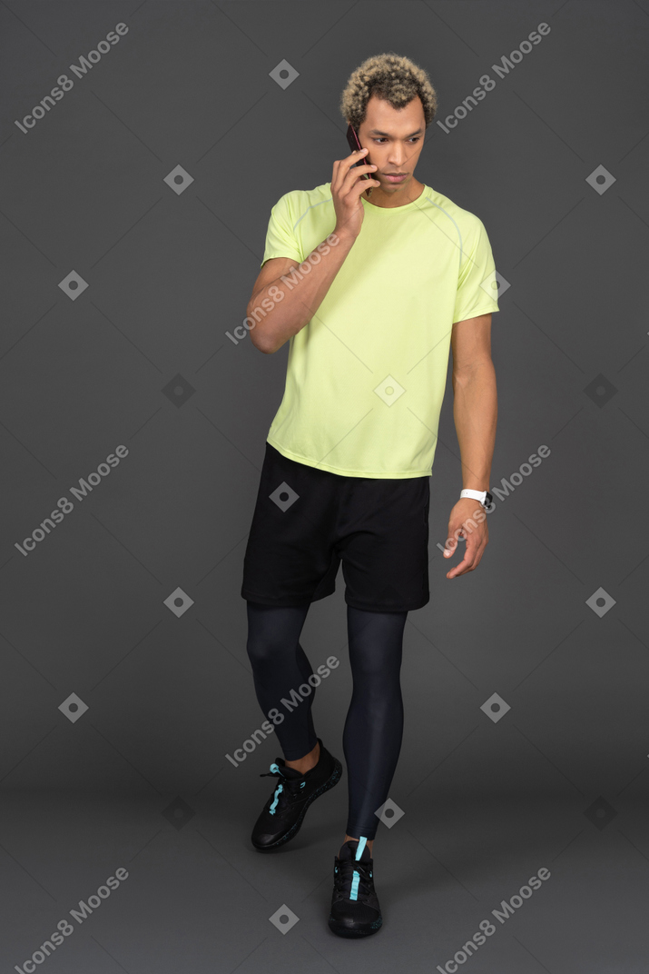 Vista frontal de un joven de piel oscura que tiene una llamada telefónica