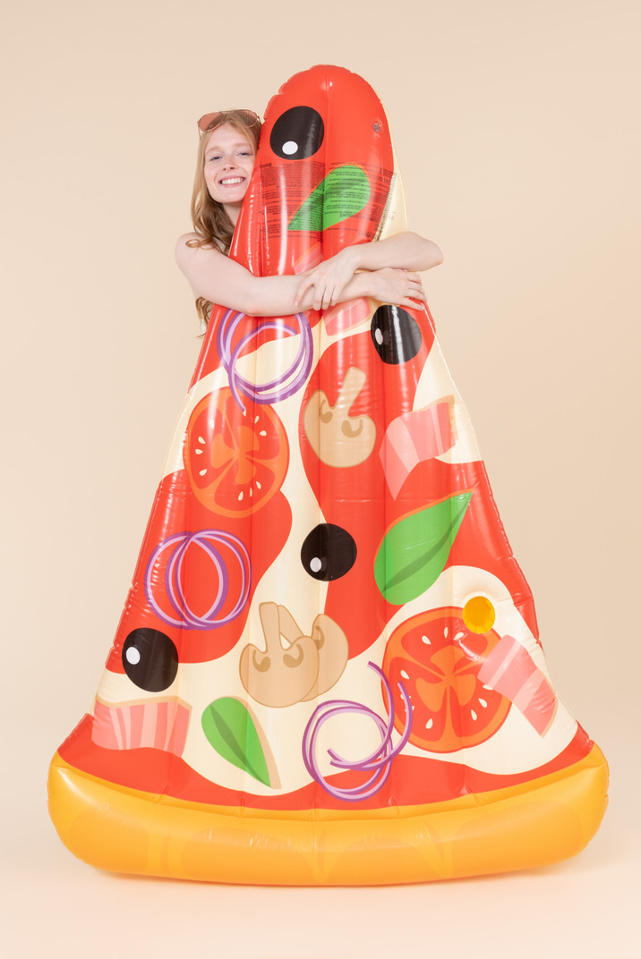 Young woman standing behind pizza mattress and hugging it