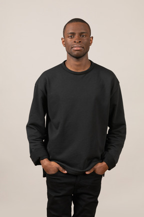 Jeune homme en tenue noire debout avec les mains dans les poches