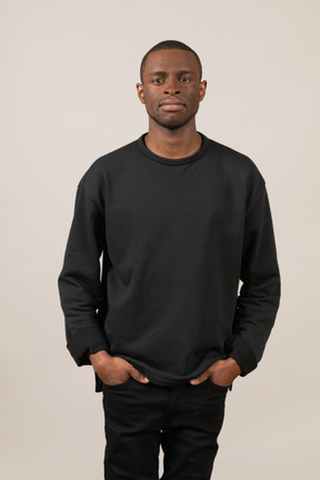 Young man in black outfit standing with hands in pockets