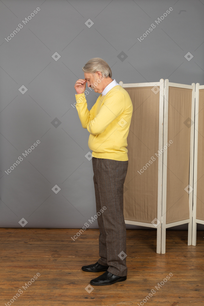 Side view of a withdrawn old man touching his head
