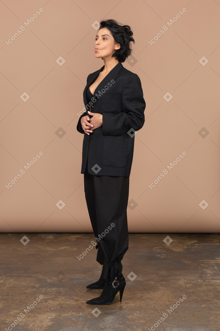 Dreiviertelansicht einer geschäftsfrau in einem schwarzen anzug, die hände auf den bauch legt und schmollt