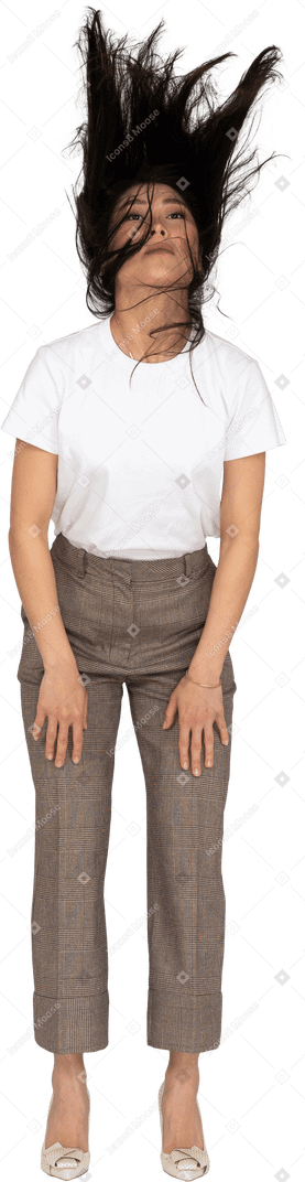 Vista frontale di una giovane donna in calzoni e t-shirt con i capelli disordinati