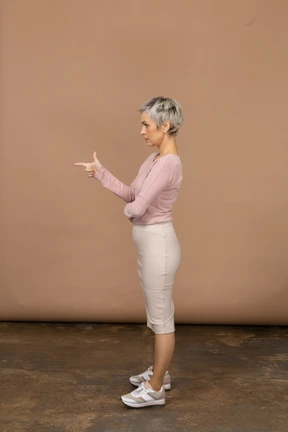 Side view of a woman in casual clothes pointing with finger