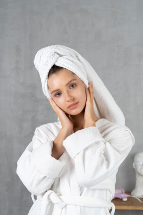 Woman in bathrobe holding her face