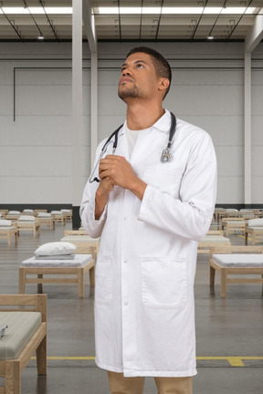 Un médico de pie en un hospital temporal y mirando hacia arriba