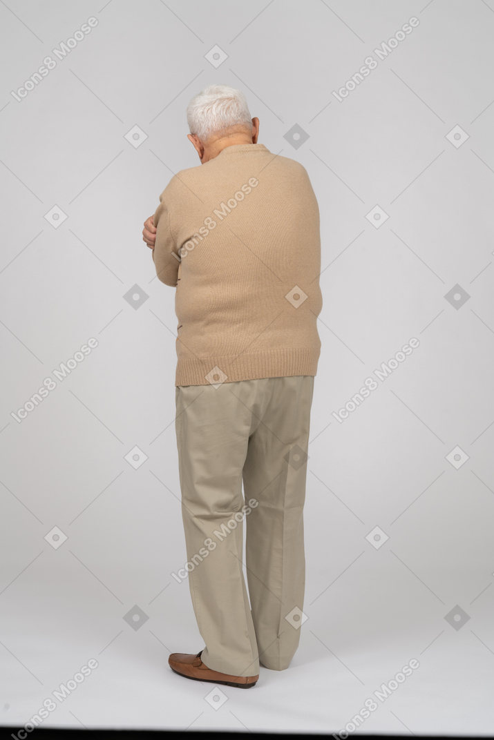 Rear view of an old man in casual clothes standing with crossed arms