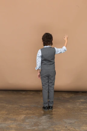 Rear view of a boy in grey suit showing ok sign