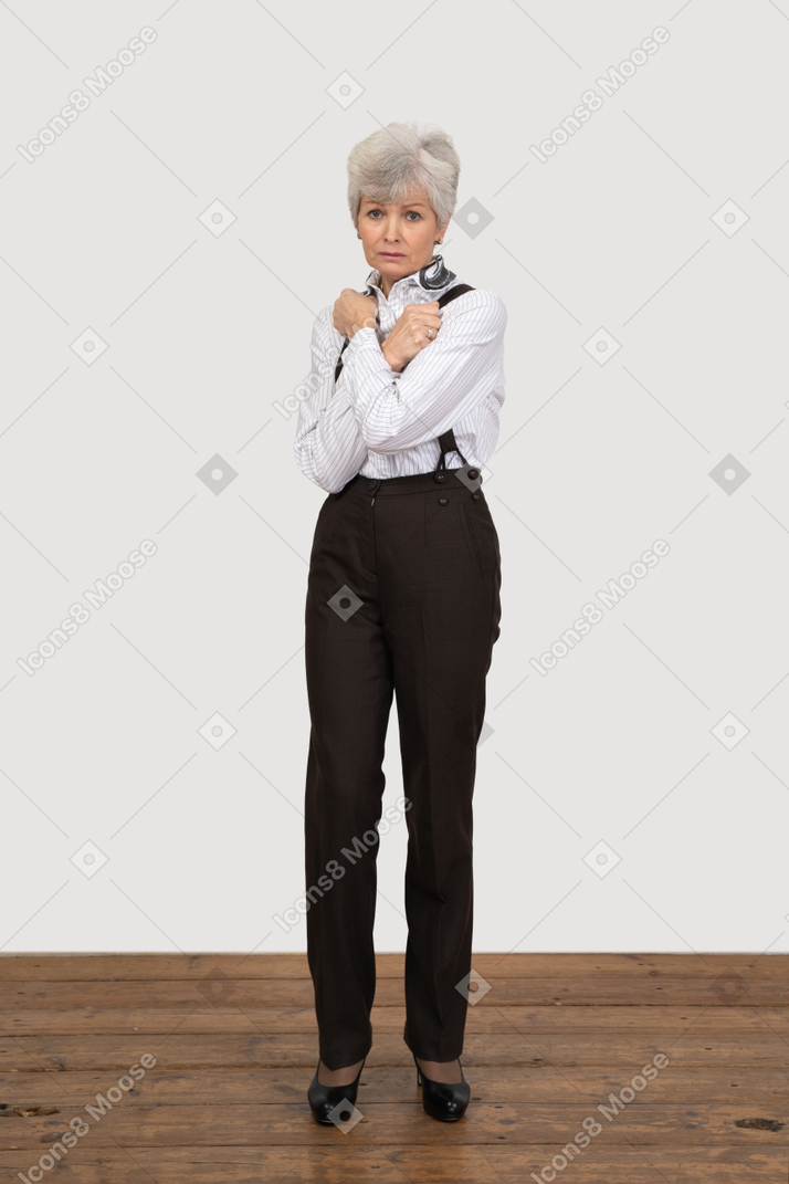 Front view of an old lady in office clothing crossing hands and clenching fists