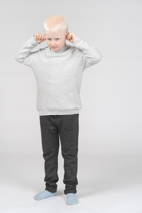 Vista frontal de um menino puxando as orelhas