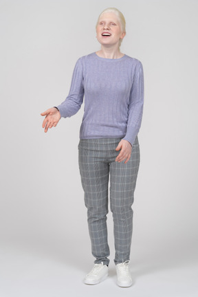 Vista frontal de una mujer joven con ropa informal riendo y gesticulando