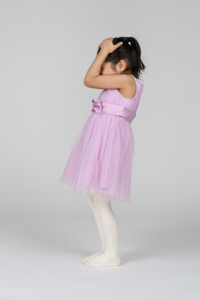 Vista lateral de una niña con un bonito vestido que cubre su cabeza