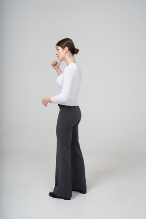Side view of a woman in black pants and white blouse gesturing