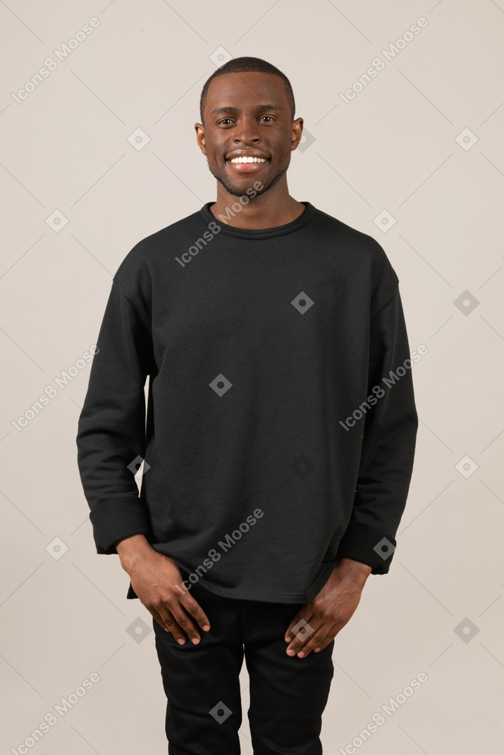 Jeune homme souriant debout avec ses mains dans les poches