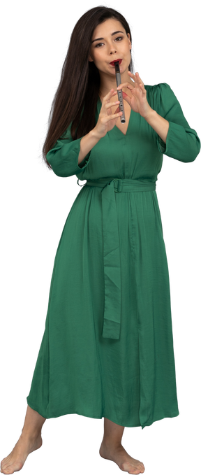 Vista frontal de uma jovem de vestido verde tocando flauta