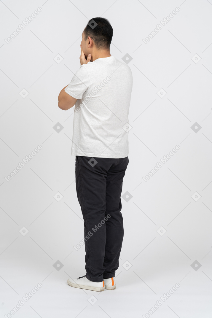 Vista di tre quarti di un uomo in abiti casual che copre la bocca con le mani