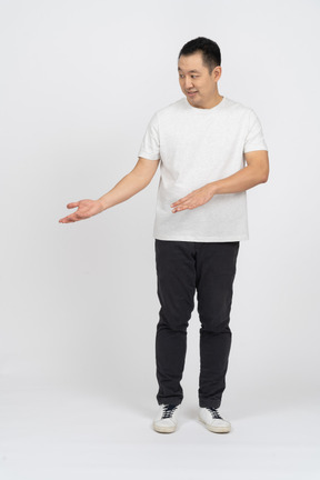 Front view of a man in casual clothes looking aside and pointing at something with a hand
