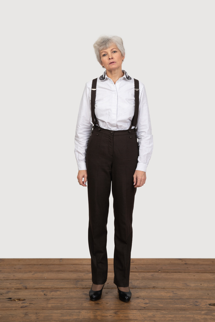 Front view of an old female in office clothes standing still in the room