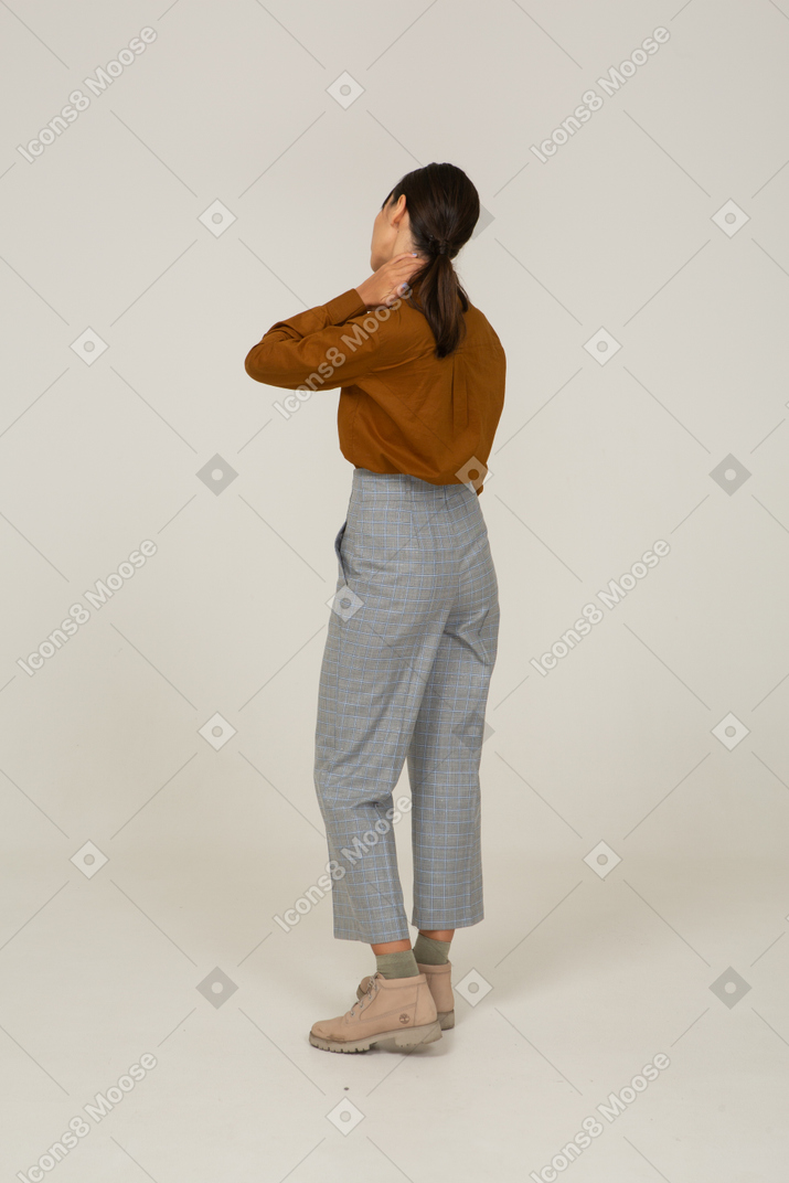 一位身着马裤和衬衫的年轻亚洲女性抚摸脖子的背影